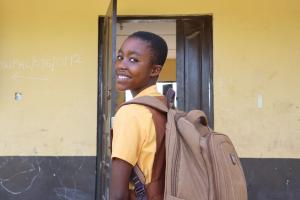 girl with backpack entering school classroom